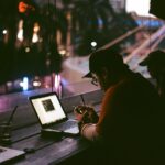 Freela remoto sem plantão: como definir horário, resposta e urgência sem perder clientes Profissional trabalhando até tarde no notebook em ambiente escuro