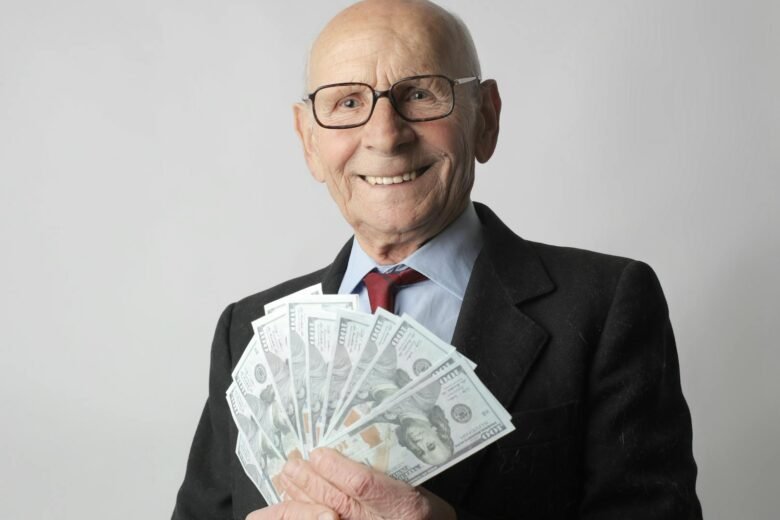 Senior man in a suit with glasses holding US dollars, symbolizing wealth and savings.