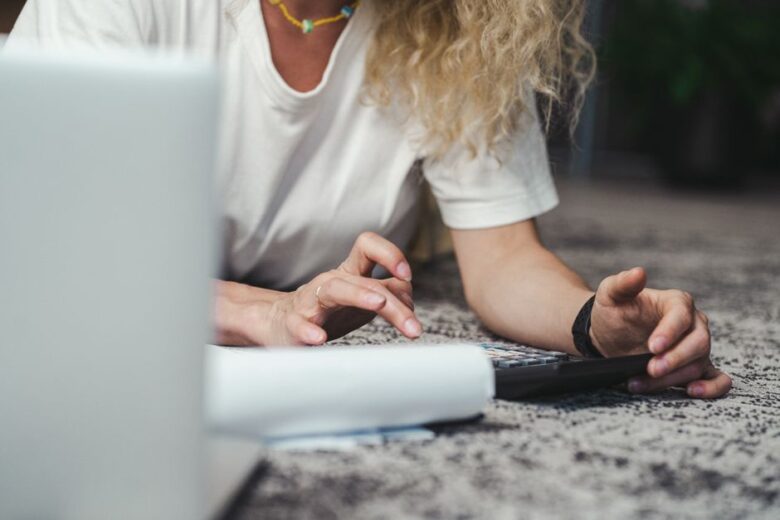 Mulher usando calculadora para precificar trabalho freelance em casa