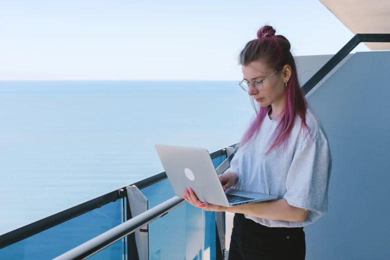 Tradutor freelancer digitando tradução em um laptop com dicionário aberto ao lado