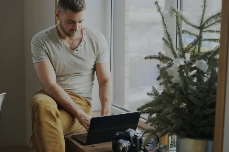 Pessoa trabalhando no notebook em home office perto de uma janela ensolarada