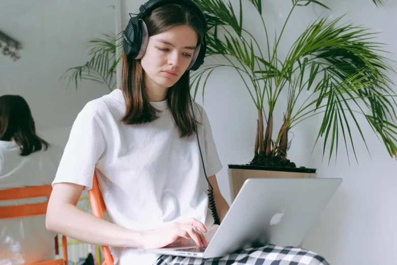 Pessoa com fones de ouvido transcrevendo áudio em um laptop, em ambiente silencioso