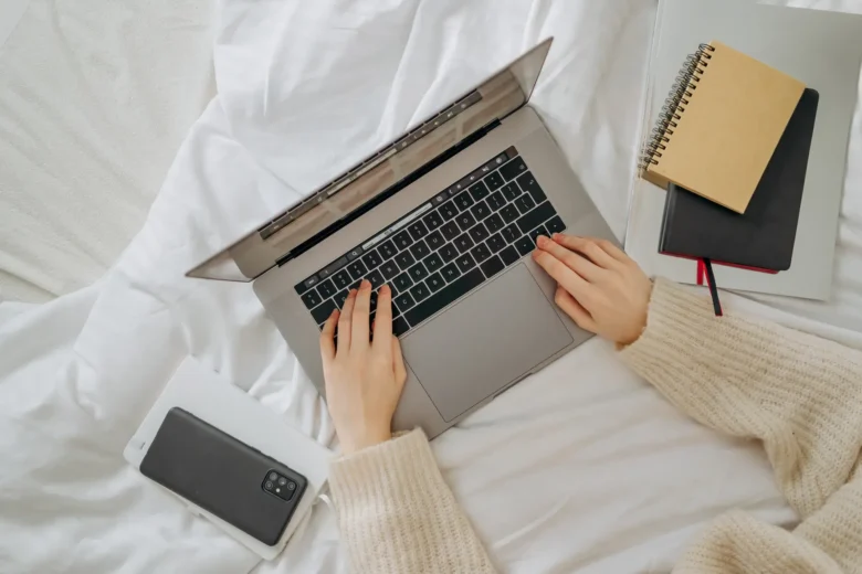 Microempreendedora individual anota o faturamento mensal em um caderno de controle financeiro ao lado do notebook