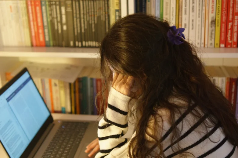 Mulher focada usando um laptop para escrever um e-book, simbolizando o trabalho de autor independente.