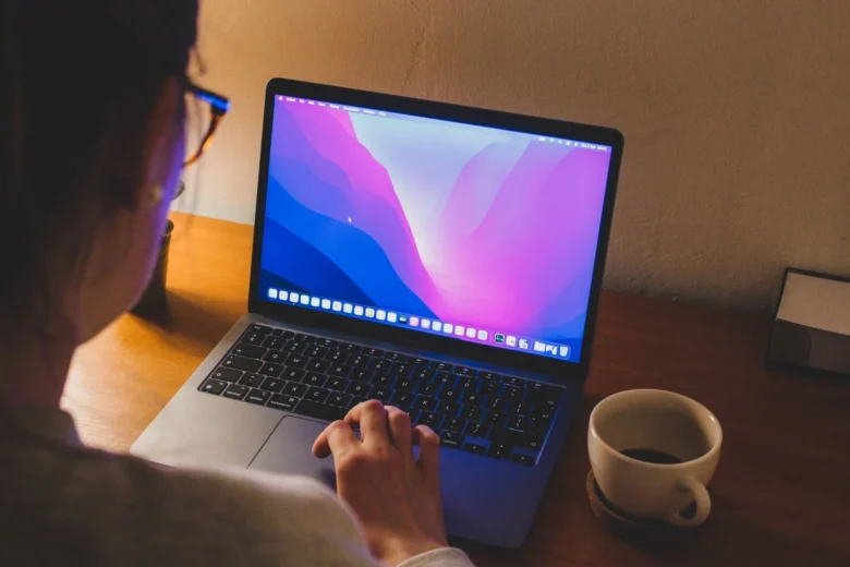 Pessoa revisando um texto no computador com caderno de anotações e caneta ao lado
