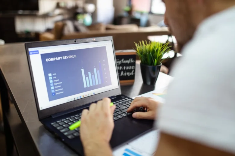 Pessoa iniciando trabalho de renda extra online em casa, com notebook e planilha de controle financeiro aberta