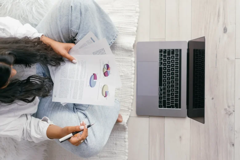 Mulher focada organizando finanças com laptop e documentos em casa, símbolo de renda extra e planejamento.
