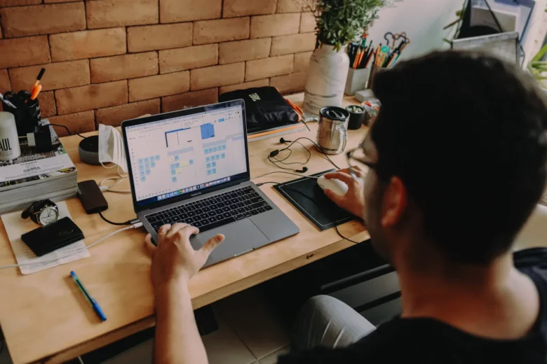 Freelancer iniciante trabalhando em um laptop em uma mesa doméstica com caderno de anotações e café
