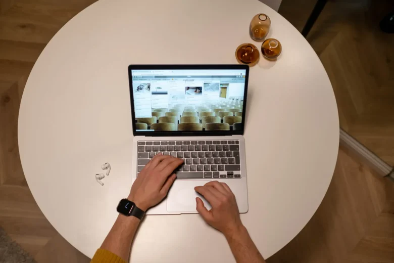 Freelancer iniciante trabalhando em laptop na mesa de casa, com caderno de anotações e café ao lado