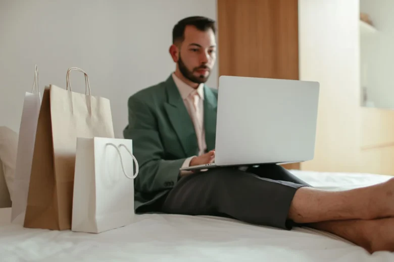 Notebook aberto em uma mesa de home office mostrando uma planilha de vendas e um cartão de crédito ao lado, representando a venda de produtos digitais pela internet sem site própri