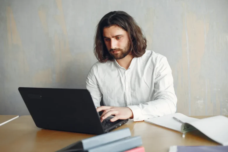 Pessoa trabalhando como freelancer de serviços locais usando um notebook em uma mesa doméstica
