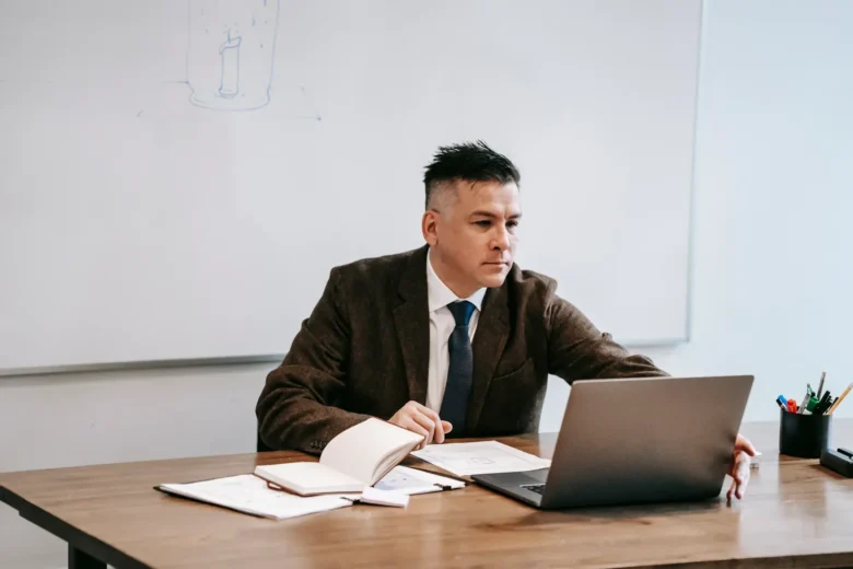 Professor de aula particular online ensinando por videochamada, com notebook aberto e caderno de anotações sobre preços por hora