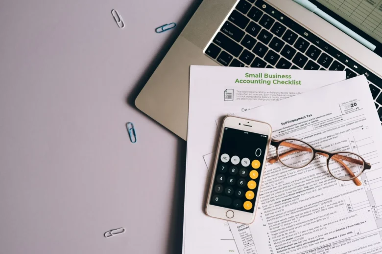 Pessoa sentada em casa fazendo contas com calculadora e notebook aberto para planejar a formalização como MEI